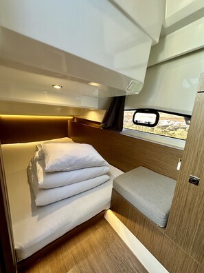 Ein kompakter, gut beleuchteter Innenraum mit einem Bett, einer kleinen Sitzecke und einem Fenster mit Blick.