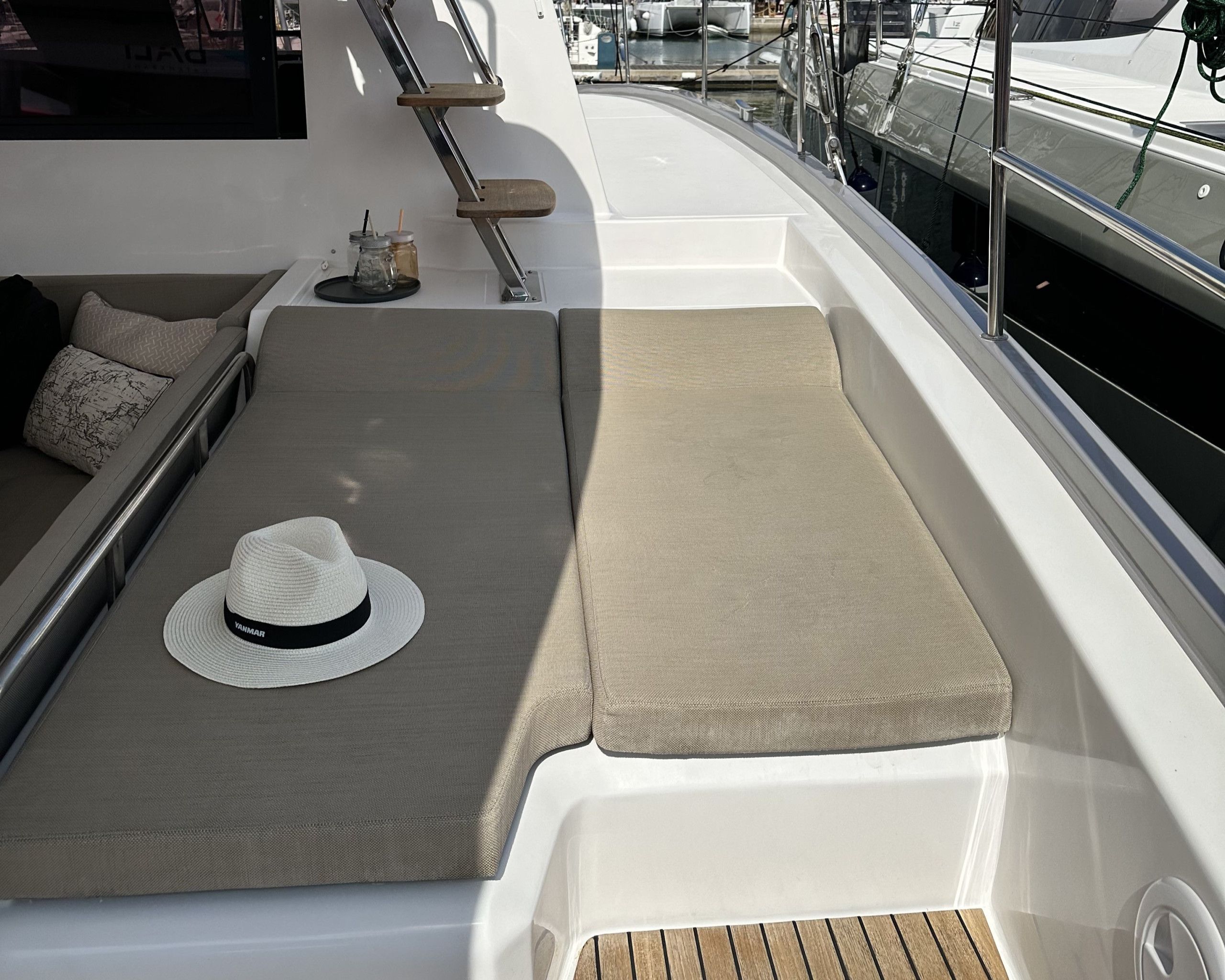 Un fauteuil de plage avec un chapeau posé dessus, un coussin et une petite table sur laquelle se trouvent un bocal en verre et une paille.
