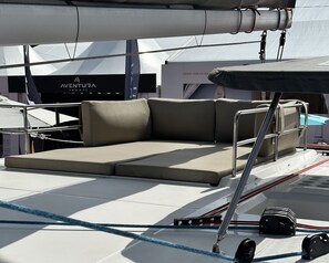 Das Deck einer Yacht mit gepolsterten Sitzgelegenheiten, Seilen und dem Logo von VENTURA YACHTS.