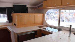 Una kitchenette compacta con una encimera, dos fregaderos y armarios de madera.