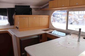 A compact kitchenette with a countertop, two sinks, and wooden cabinets. - Sun-Kissed Sailing Adventure in Islas Sarónicas (Alimos)