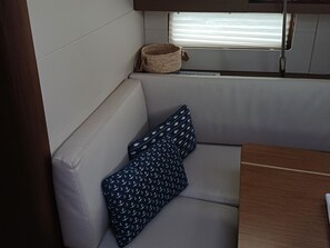 Eine kleine Küchenzeile mit Fenster, einem gewebten Korb und einer gepolsterten Sitzecke mit gemusterten Kissen.