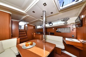 A compact interior with a dining area, a small kitchenette, and a seating area with a window. - Sun-Kissed Sailing Adventure in Zadar, Croatia (Bibinje)