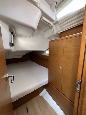 Ein kompaktes Wohnmobil-Interieur mit einem Stockbett, einem Holzkasten und einem kleinen Fenster.