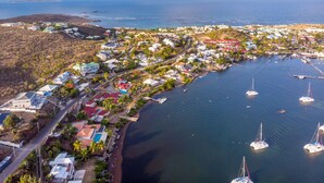 An aerial view of a coastal town with houses, a marina, and boats.