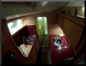 A compact kitchen with a stove, sink, and a small window.