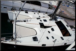 A white yacht with multiple windows, a mast, and a cabin structure.
