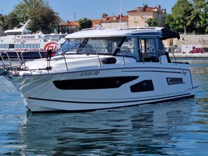 Eine weiße Motoryacht mit Kabine und Windschutzscheibe, inklusive Kennnummer.