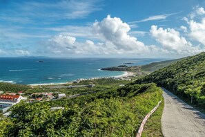 Une route côtière offrant une vue sur l’océan et une île lointaine.
