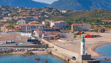 Un pueblo costero con un faro destacado, una playa y edificios residenciales.
