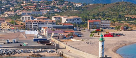 A coastal town with a prominent lighthouse, a beach, and residential buildings.