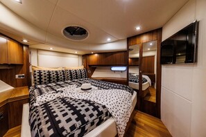 A compact, well-lit interior with a bed, bedside tables, a mirror, and a television.