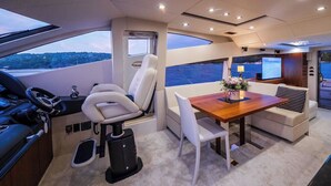 A yacht interior with a steering wheel, a dining table with chairs, a TV, and a view of the sea. - Sun-kissed Sailing Adventure in Split-Dalmatia, Croatia (Seget Donji)