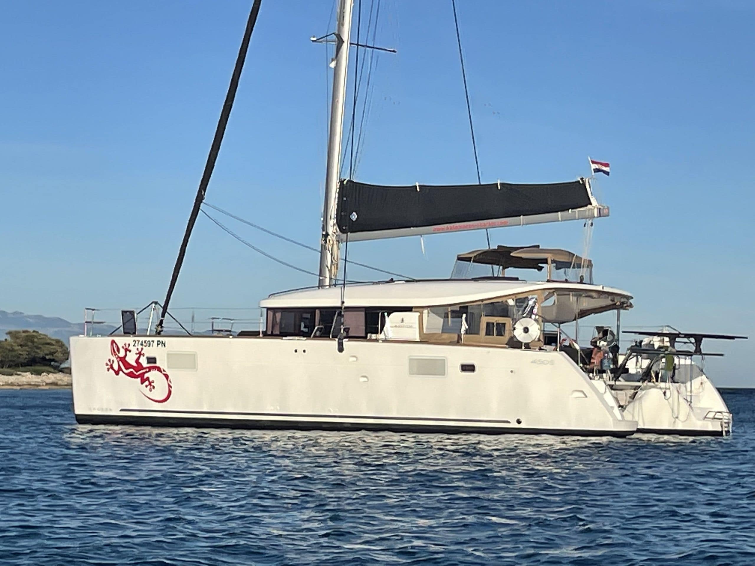 Un grand yacht à la coque blanche, orné d’un logo rouge et arborant le drapeau néerlandais.