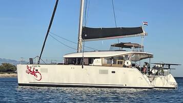 Un grand yacht à la coque blanche, orné d’un logo rouge et arborant le drapeau néerlandais.