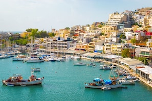 Un puerto marítimo costero con numerosos barcos amarrados, rodeado de edificios muy juntos.