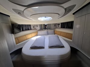A compact, well-lit interior with a central bed, built-in seating, and a skylight. - Sun-Kissed Sailing Adventure in Sibenik, Croatia (Primošten)
