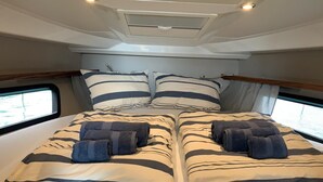 A double bed with striped bedding and pillows, a headboard, and a window with a view of the water. - Sun-kissed Sailing Adventure in Split-Dalmatia, Croatia (Trogir)