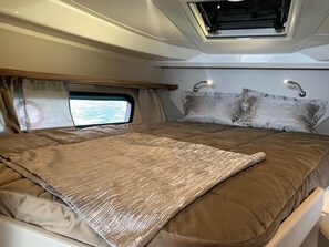 Een bed met hoofdeinde, een raam met gordijnen en een dakvenster.