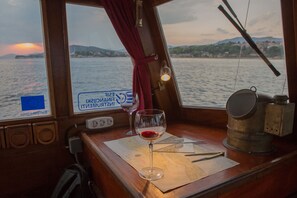 A wooden table with a map, a wine glass, and a metal container on a ship deck. - Sun-Kissed Sailing Adventure in Split, Croatia (Split)