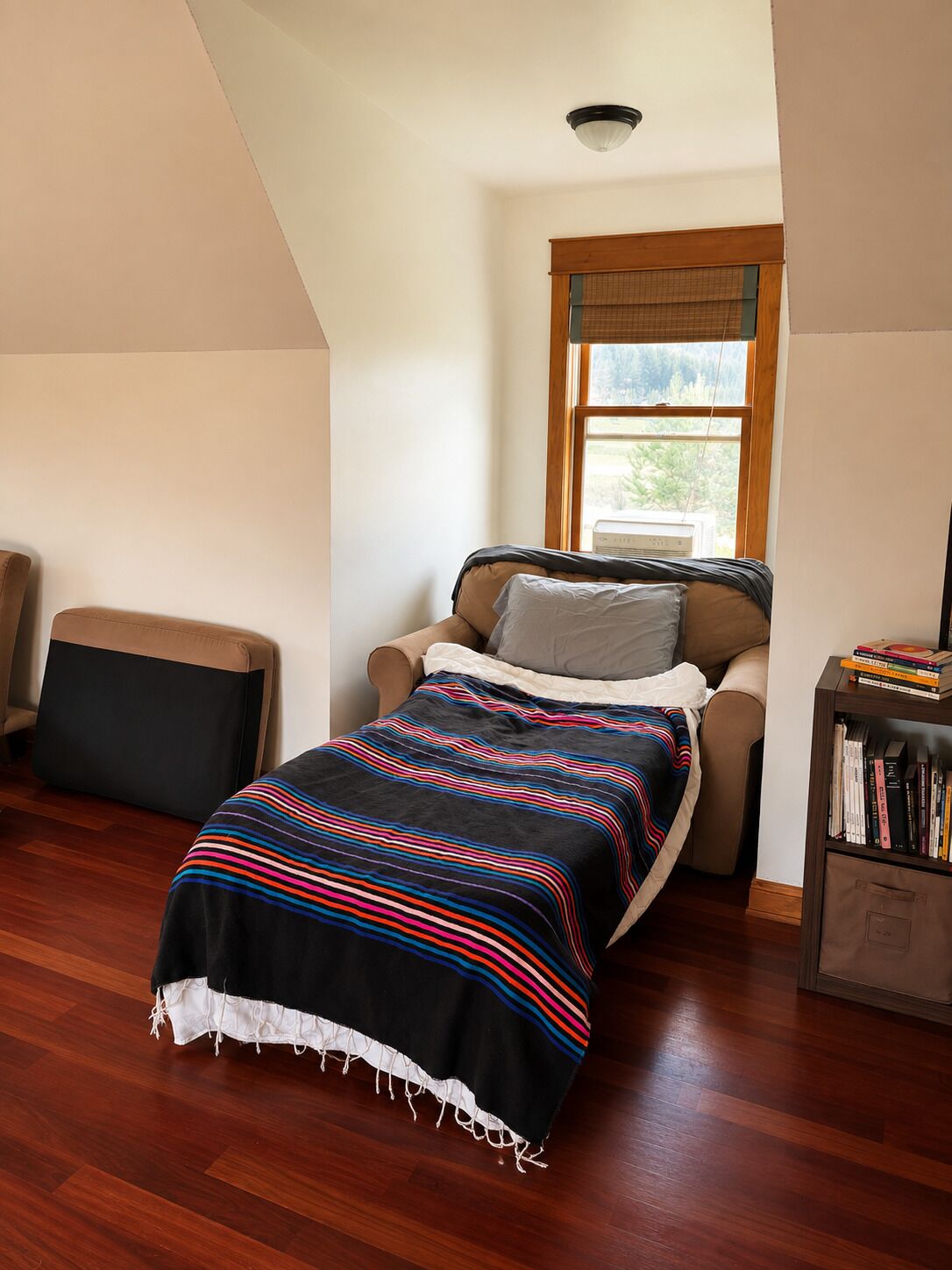 Une chambre à coucher comprenant un lit, une chaise, une bibliothèque et une fenêtre donnant sur un paysage verdoyant.