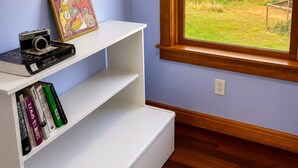 A room with a window, a white shelf with books, and a camera.