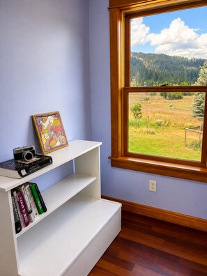 Una habitación con ventana, un estante blanco con libros y una cámara.