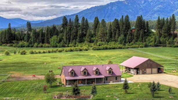 A rural property with a large house, a barn, and a field with horses.