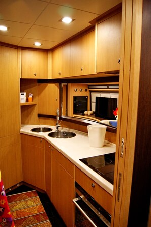 A compact kitchen with wooden cabinets, a double sink, and a microwave.