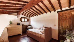 Un dormitorio con cama, cómoda, ventana y puerta de madera.