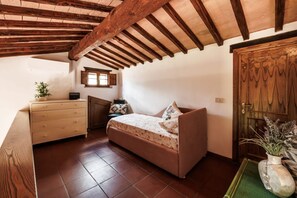 A bedroom with a bed, dresser, window, and wooden door. - A spacious 120 sqm apartment, ideal for six guests, situated within a charming estate in the Chianti hills in a peaceful setting along a traffic-free road. Guests have access to a private garden with a furnished patio - perfect for enjoying the outdoors  (Castelnuovo Berardenga)