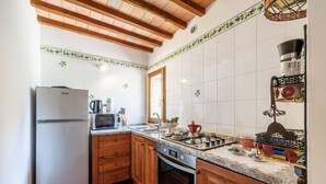Una cocina con gabinetes de madera, un refrigerador de acero inoxidable, un microondas, una estufa y un fregadero.