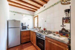 A kitchen with wooden cabinets, a stainless steel refrigerator, a microwave, a stove, and a sink. - A spacious 120 sqm apartment, ideal for six guests, situated within a charming estate in the Chianti hills in a peaceful setting along a traffic-free road. Guests have access to a private garden with a furnished patio - perfect for enjoying the outdoors  (Castelnuovo Berardenga)