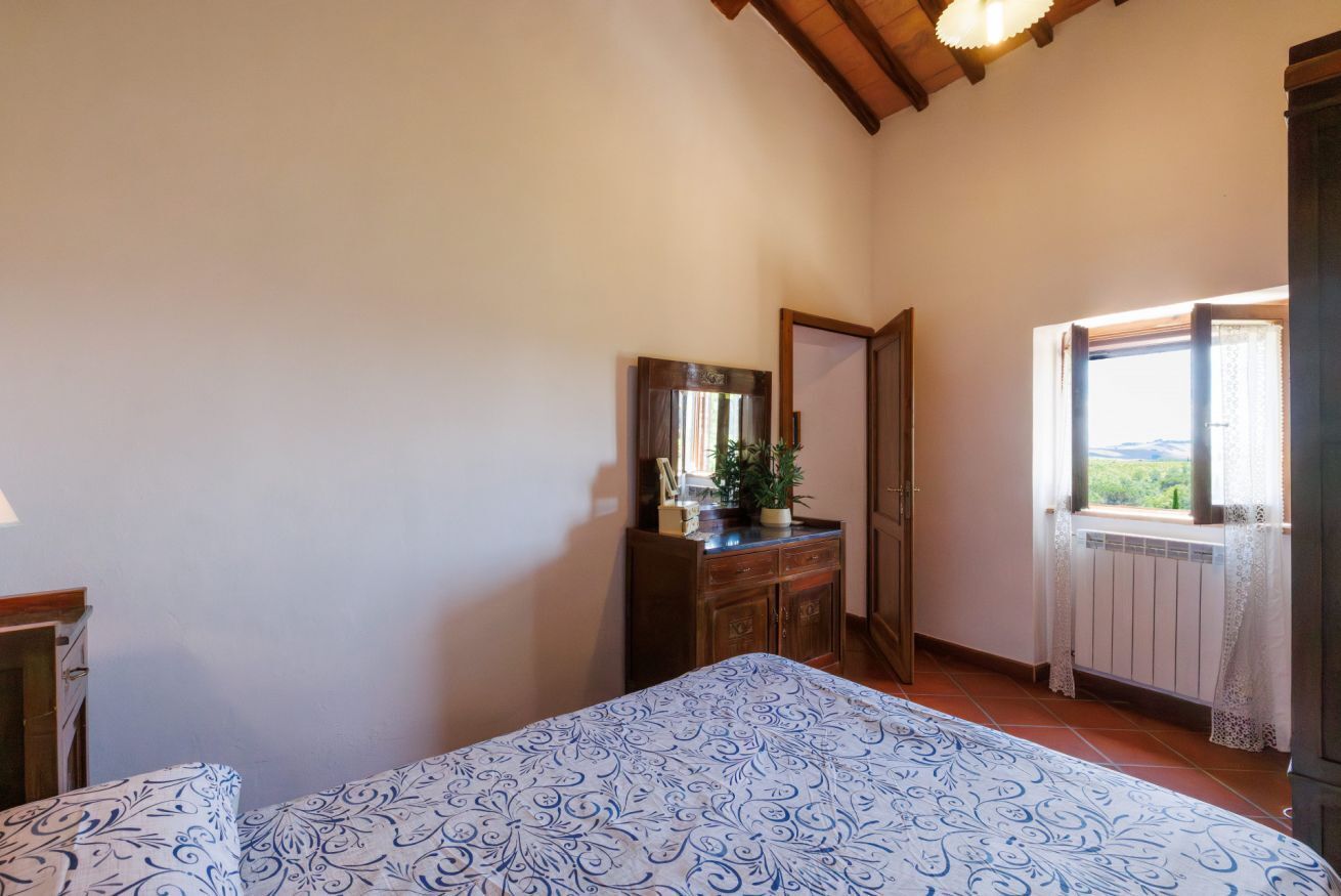 Un dormitorio con cama, cómoda, espejo y ventana con vistas.