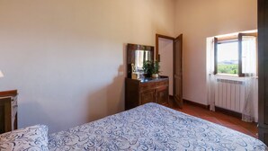 Un dormitorio con cama, cómoda, espejo y ventana con vistas.