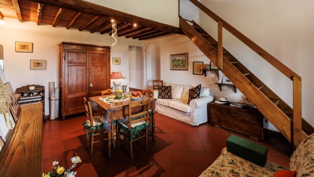 Una sala acogedora con una escalera de madera, una mesa de comedor con sillas y un sofá.