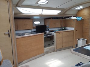 Une cuisine de taille réduite, avec des meubles de rangement en bois, une cuisinière et une petite fenêtre.