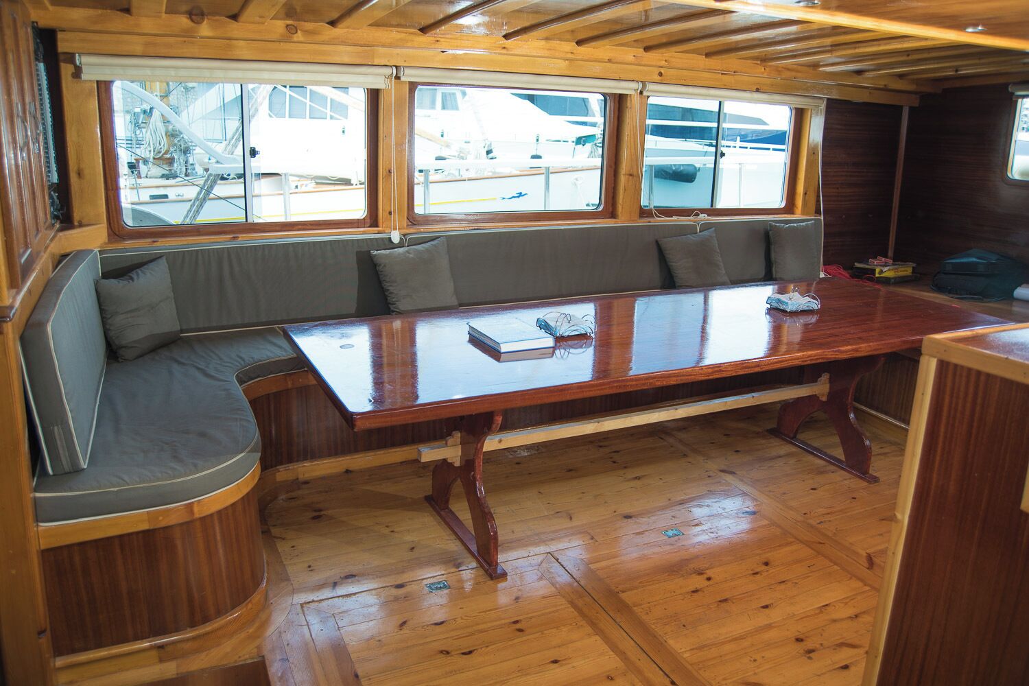 Eine Holzhütte mit Holzeinrichtung, einem zentralen Tisch und Sitzgelegenheiten mit Kissen.