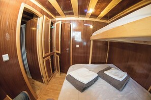 Ein gemütlicher, hölzerner Innenraum mit einem Etagenbett, einem kleinen Schrank und einer Tür zu einem anderen Raum.