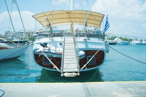 Eine Yacht liegt in einer Marina vor Anker, mit sichtbarer Deckfläche, Kabine und Flagge.