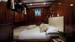 Ein Zimmer mit Holzwänden, einem Bett, einem Gemälde, einem Nachttisch und einer Zeitschrift.