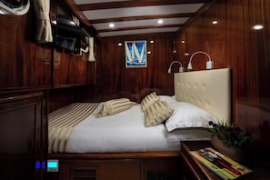 A wooden-paneled room with a bed, a painting, a nightstand, and a magazine. - Sun-Kissed Sailing Adventure in Split, Croatia (Split)