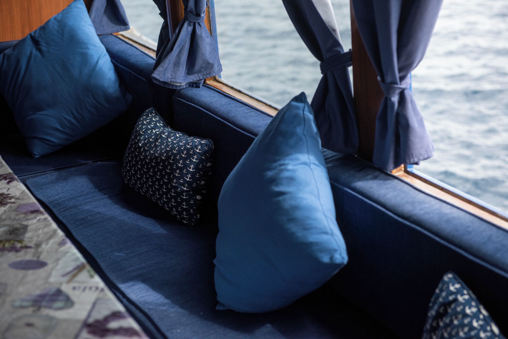 A boat interior with blue cushions and curtains.