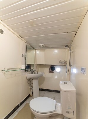 Un baño pequeño y funcional con inodoro, lavamanos y ducha.