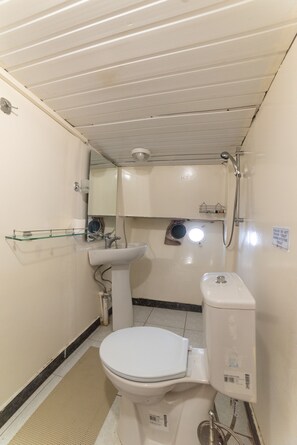 Et lille badeværelse med toilet, vask og brusebad.