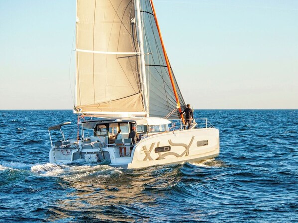 Eine Segelyacht mit Kabine, Deckssitzen und einer Person, die am Heck steht.