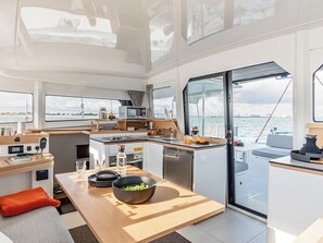 Eine kleine Pantryküche mit Spüle, Herd und Mikrowelle; ein Essbereich mit einer Salatschüssel; und Meerblick durch große Fenster.