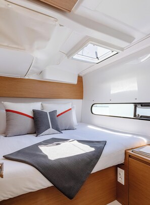 Ein gemütliches, helles Blockhaus mit Bett, Kissen und einem kleinen Tisch.