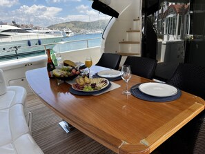 A yacht dining area with a table set for two, a view of the marina, and a boat in the background. - Sun-Kissed Sailing Adventure in Sibenik, Croatia (Rogoznica)