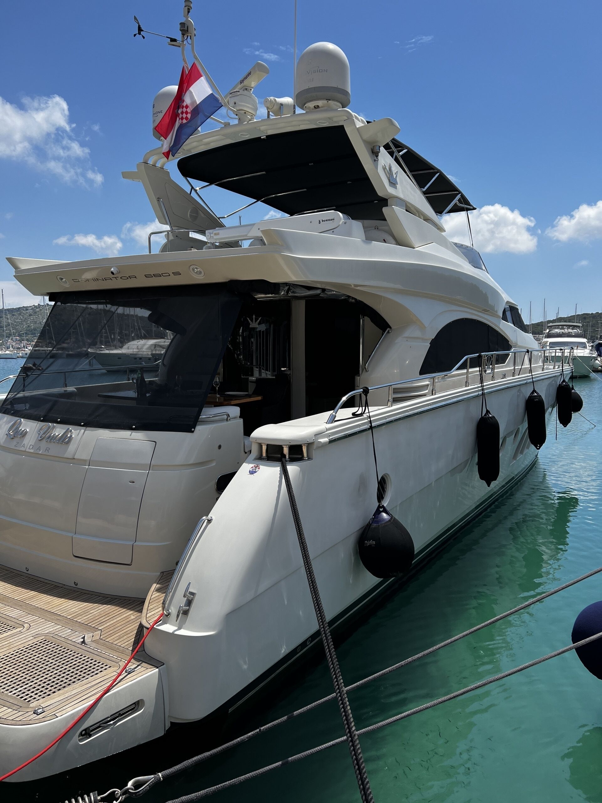 A yacht docked at a marina with a clear sky.